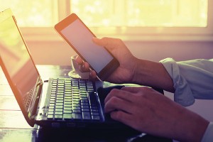 Morning work on laptop with phone in hand. Photo: ©iStock.com/jakkapan21
