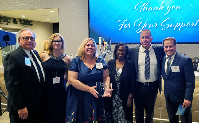 Rollins employees accept the Volunteer of the Year award. From left, Paul Youngpeter, Assistant Division President; Kim Youngpeter, Application Development Managing Director; Kelly Solomon, Application Development Director; Georgetta Sullivan, Programmer Analyst; Kevin Morrison, VP ITC Operations; and Todd Mininger, Desktop Support Manager. PHOTO: ROLLINS