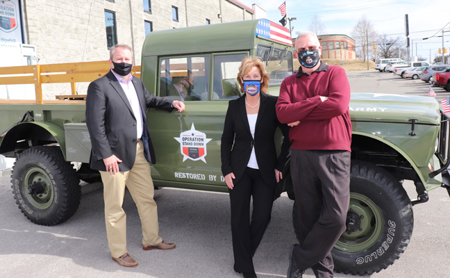 From left, FMC's Tom Wharton, Arrow Exterminators' Marie Horner, and Catchmaster's Dr. Stan Cope stand in front of a truck used in military parades that is parked in front of the new veterans' apartment complex. The trio represented the PestVets group and delivered the donation check. PHOTO: ARROW EXTERMINATORS