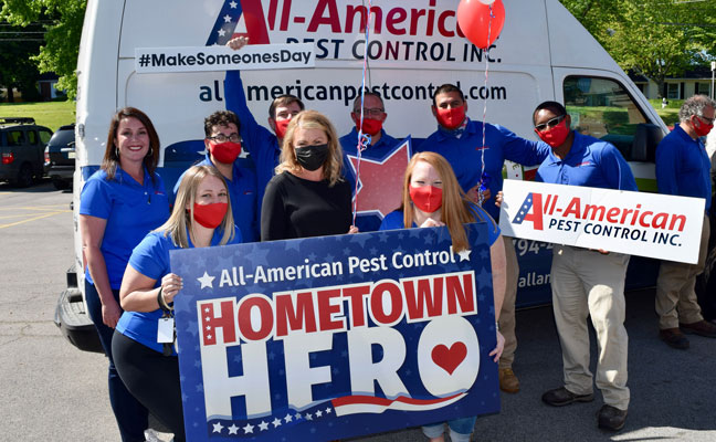 Brandi Nunnery, in black mask, is surrounded by members of the All-American Pest Control team after the Hometown Hero award ceremony. PHOTO: ALL-AMERICAN PEST CONTROL