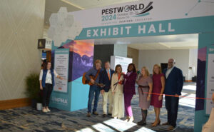 The ribbon cutting ceremony marked the official start of PestWorld 2024. Pictured, from left, are NPMA Director of Meetings & Exhibits Megan Moloney, Chris Collins of the John Denver Tribute Band and National Pest Management Association board of directors Bob Dold, Marillian Missiti, Faye Golden, Dominique Stumpf, Emily Thomas Kendrick and Mike Bullert. PHOTO: PMP STAFF