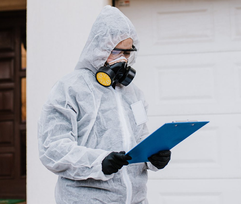 Technician wearing a hazmat suit holding a clipboard
